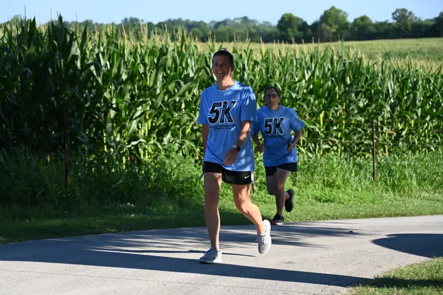 Runners on the camp road beside the cornfield during the Family Camp 5K