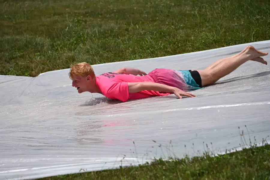 A camper sliding down the wet sheeting on the hill
